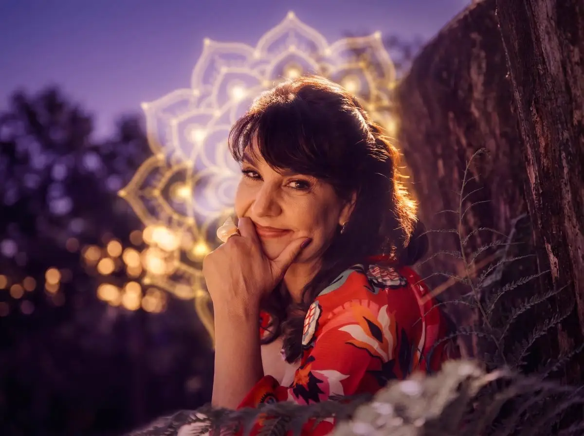 Cristina Camargo sorrindo, com uma mandala de luz dourada atrás