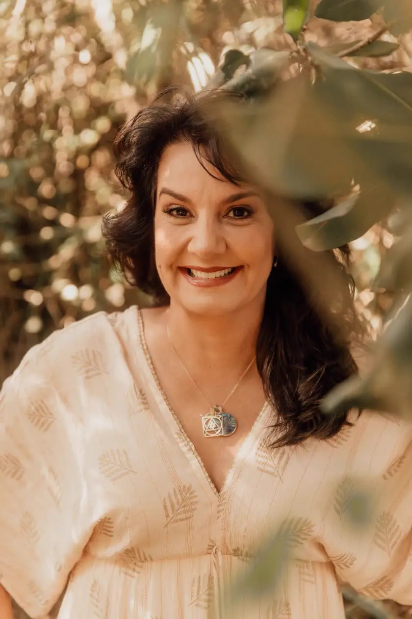 Cristina Camargo sorrindo entre as folhas